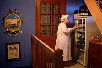 Eine Peson steht in Nachthemd und Mütze vor einem Kühlschrank mit Getränken | © Touristikgemeinschaft Hohenlohe e. V.| Winklers Weinstube