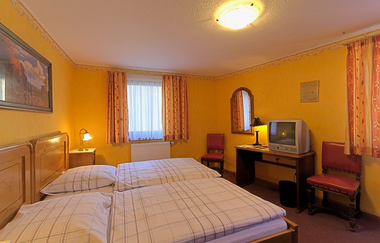 Das Zimmer ist gelb, es steht ein Doppelbett und ein Schreibtisch mit Stühlen im Zimmer | © Touristikgemeinschaft Hohenlohe e. V.| Winklers Weinstube