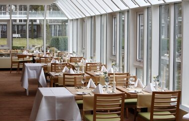 Restaurantbereich an der Glasfassade mit Tischen und Stühlen | © Best Western Premier Parkhotel