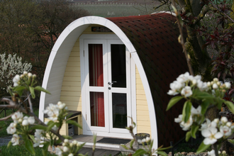 Der Campingpod von außen ist umrahmt von vielen Bäumen. | © Touristikgemeinschaft Hohenlohe e. V. | Burgstallhof