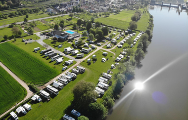 Blick von oben auf einen Campingplatz mit vielen Wohnmobilen. Rechts daneben fließt ein Fluss. Neckarzimmern im Odenwald. | © Wohnmobilstellplatz + Campingplatz CIMBRIA