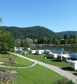 Campingplatz mit einer Reihe von weissen Wohnwägen. Direkt am Platz vorbei fliesst ein Fluss, der Neckar. Im Hintergrund ein bewaldeter Berg. Eberbach im Odenwald. | © Campingpark Eberbach