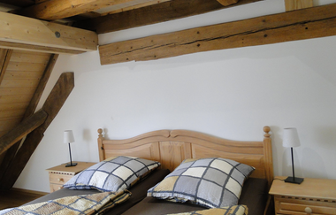 Schlafzimmer in Carles Scheunenhof mit Doppelbett und karierter Bettwäsche | © Touristikgemeinschaft Hohenlohe e. V. | Familie Carle