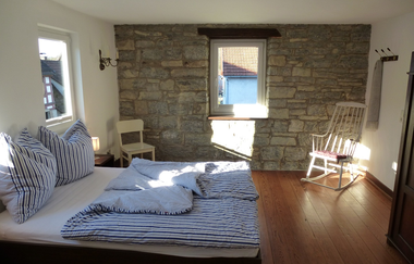 Doppelbett im Schlafzimmer mit Natursteinwand und Parkettboden | © Touristikgemeinschaft Hohenlohe e. V. | Klaus Schirmer