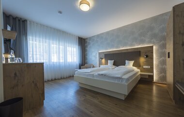 Das Zimmer mit Doppelbett ist in warmen Holztönen eingerichtet | © Touristikgemeinschaft Hohenlohe e. V. | Thomas Rathay