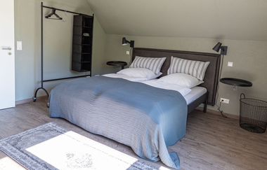 Modern eingerichtetes Schlafzimmer mit gemütlichem Doppelbett im Ferienhaus Naturton | © Hohenlohe Schwäbisch Hall