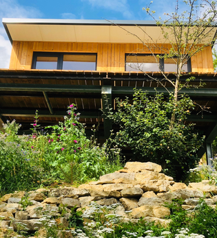 Das Haus steht auf einer Bodenplatte und ist von einer Mauer mit Blumen umgeben | © Touristikgemeinschaft Hohenlohe e. V.| Katharina Schmieg