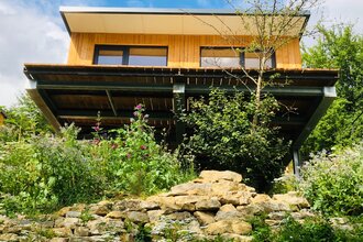 Das Haus steht auf einer Bodenplatte und ist von einer Mauer mit Blumen umgeben | © Touristikgemeinschaft Hohenlohe e. V.| Katharina Schmieg