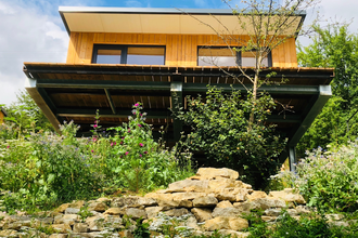 Das Haus steht auf einer Bodenplatte und ist von einer Mauer mit Blumen umgeben | © Touristikgemeinschaft Hohenlohe e. V.| Katharina Schmieg