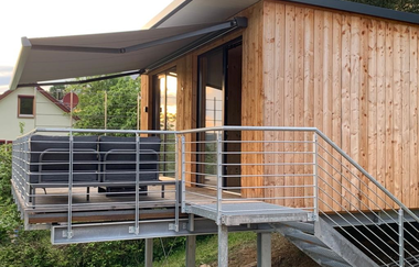 Das Ferienhaus ist aus Holz gebaut und hat außen eine Treppe zum Markise | © Touristikgemeinschaft Hohenlohe e. V.  | Katharina Schmieg
