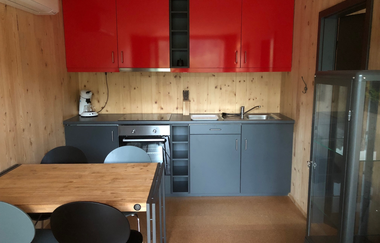 Eine Küchenzeile in rot und grau, ein Tisch mit Stühlen und ein Kühlschrank stehen im Wohnraum | © Touristikgemeinschaft Hohenlohe e. V.| Katharina Schmieg