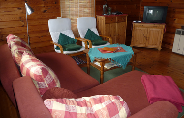 Im Wohnzimmer steht ein Sofa, Sessel und ein TV-Gerät | © Touristikgemeinschaft Hohenlohe e. V. | Ferienhof Hettinger