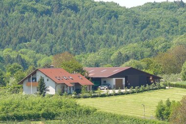 Der Ferienhof mit Haus und Scheune liegt inmitten der grünen Landschaft | © Touristikgemeinschaft Hohenlohe e. V.