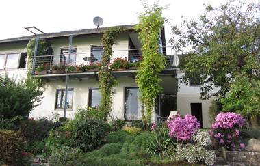 Die Ansicht von außen mit der Terrasse und dem grünen Garten | © Touristikgemeinschaft Hohenlohe e. V.  | Ferienwohnung am Kocherhang