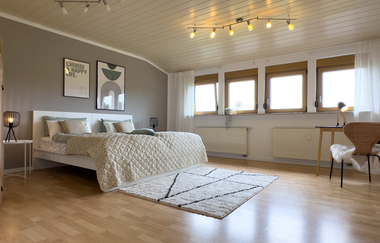 Schlafzimmer der großen Ferienwohnung: weißes Bett mit Nachttischschränkchen und Schreibtisch mit Stuhl | © Neckar-Zaber-Tourismus e.V.