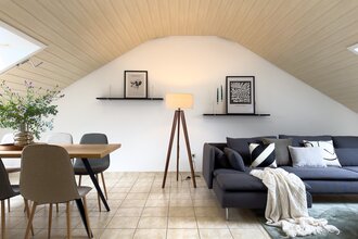 Wohnzimmer der großen Ferienwohnung: dunkelgraue Couch mit Kissen und Decken und ein Tisch mit mind. vier Stühlen | © Neckar-Zaber-Tourismus e.V.