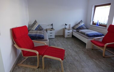 Wohn- und Schlafraum der Ferienwohnung: zwei Einzelbetten und zwei rote Sesselstühle | © Neckar-Zaber-Tourismus e.V.