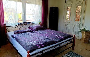 Schlafzimmer 2 mit lila Bettwäsche, Schrank und großen Fenstern | © Neckar-Zaber-Tourismus e.V.