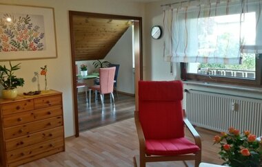 Das Wohnzimmer mit bequemem Sessel und Ausblick auf den Balkon | © Touristikgemeinschaft Hohenlohe e. V. |  Ferienwohnung Fehrenbach