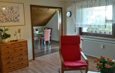 Das Wohnzimmer mit bequemem Sessel und Ausblick auf den Balkon | © Touristikgemeinschaft Hohenlohe e. V. |  Ferienwohnung Fehrenbach