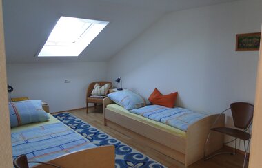 Zwei Einzelbetten mit jeweils einem Nachttischschrank mit Lampe und mehrere Stühle | © Neckar-Zaber-Tourismus e.V.