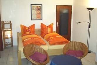 Im Wohnraum steht ein Doppelbett un zwei Stühle | © Touristikgemeinschaft Hohenlohe e. V. | Ferienwohnung Roll