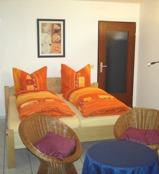 Im Wohnraum steht ein Doppelbett un zwei Stühle | © Touristikgemeinschaft Hohenlohe e. V. | Ferienwohnung Roll