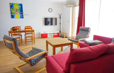 Wohn- Esszimmer mit roter Couch und grauen Stühlen und ein Esstisch mit vier Holzstühlen | © Neckar-Zaber-Tourismus e.V.