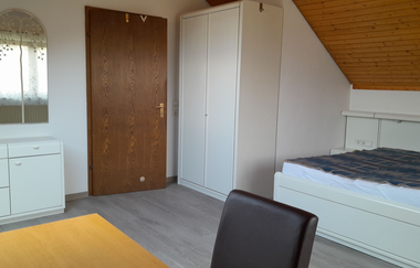 Schlafzimmer der Ferienwohnung mit kleinem Tisch, Bett und Kommoden | © E. Hügler