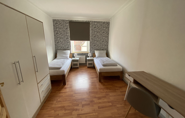 Schlafzimmer mit zwei Einzelbetten, Nachttischen, Kleiderschrank, Schreibtisch und Stuhl, Fenster mit Rollladen | © Ferienwohnung Etzl