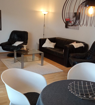 Wohnzimmer mit Couch, Sessel, Essecke und TV | © Dörr