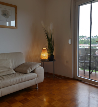 Wohnzimmer mit Blick auf den Balkon, Beige Ledercouch und Holzboden, Lampe | © Hopf