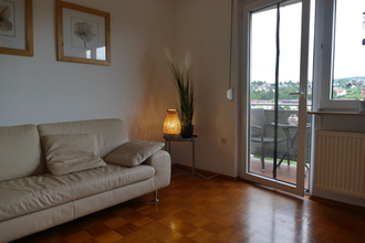 Wohnzimmer mit Blick auf den Balkon, Beige Ledercouch und Holzboden, Lampe | © Hopf