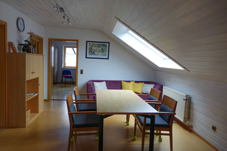 Esstisch mit vier Stühlen, eine violette Couch mit gelben und weißen Kissen und ein Holzschrank mit Deko | © Neckar-Zaber-Tourismus e.V.