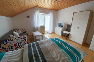 Zimmer mit einem Bett, einer Couch + Tisch und einem großen weißen Kleiderschrank | © Neckar-Zaber-Tourismus e.V.