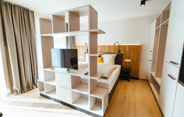 Aufnahme eines Zimmers, Bett mit Nachttischschränkchen und ein weißes Regal davor mit Fernseher, großer weißer Schrank rechts davon | © Neckar-Zaber-Tourismus e.V.