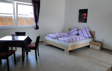 Wohn- und Schlafraum mit Doppelbett und einem quadratischen Tisch mit mind. 3 Stühlen | © Neckar-Zaber-Tourismus e.V.