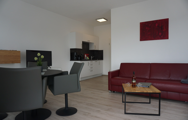 Wohnraum mit dunkelroter Couch, Couchtisch und Tisch mit mehreren Stühlen | © Neckar-Zaber-Tourismus e.V.