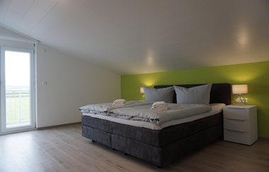 Zimmer in Terrassenlage, leichte Dachschräge, Doppelbett und zwei Nachttischschränkchen jeweils mit Lampe | © Neckar-Zaber-Tourismus e.V.