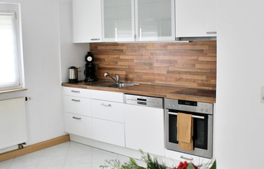 Küchenzeile mit weißer Front, ein Tisch mit einem Blumenstrauss steht davor | © Touristikgemeinschaft Hohenlohe e. V. | Melanie-Isabell Rettich