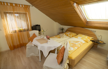 Gelb und Weiß eingerichtetes Doppelzimmer, ein kleiner Tisch mit zwei Stühlen und Kissen. | © Neckar-Zaber-Tourismus e.V.