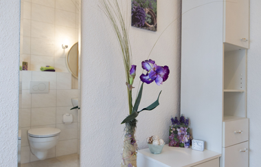 Aufnahme der weißen Schränke (einer groß, einer klein) und des Hockers, darüber ein langer Spiegel, des Badezimmers. | © Neckar-Zaber-Tourismus e.V.