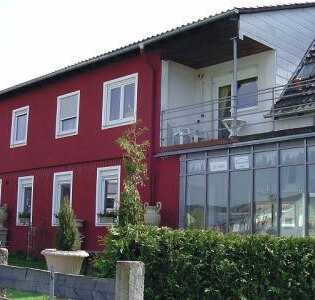 Ein rotes Haus mit einem kleinem Vorgarten. | © Gästehaus Paradies