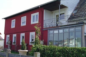 Ein rotes Haus mit einem kleinem Vorgarten. | © Gästehaus Paradies