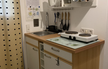 Kleine Küchenzeile mit Spüle, Herd, Küchenutensilien an der Wand und Kaffeemaschine auf der Arbeitsplatte | © Gästehaus Sabine