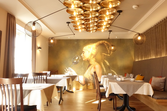 Frühstücksraum mit goldenem Bild von einer Frau im Hintergrund. Rechts gibt es eine Sitzbank mit Kissen und links stehen die Tische am Fenster. | © Neckar-Zaber-Tourismus e.V.