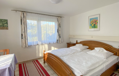 Aufnahme des Doppelzimmers. Breites Doppelbett neben einem recht großen Fenster. Rot und beige Teppiche säumen den Fliesenboden und es gibt einen Tisch mit mindestens zwei Holzstühlen. | © Neckar-Zaber-Tourismus e.V.