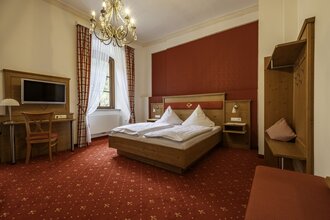 Gemütliches Doppelbett mit Fernseher und Kofferablage | © Touristikgemeinschaft Hohenlohe e. V. | Dominik Rau