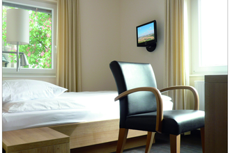 Ein Komfortzimmer mit Bett, TV, Schreibtisch und Stuhl | © Touristikgemeinschaft Hohenlohe e. V. | Hotel-Cafe Mainzer Tor