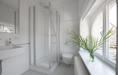 Weiß gehaltenes Bad mit Duschkabine, Waschbecken und Toilette | © Hotel Kredell